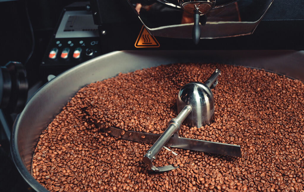Ricco Coffee – Craft Roasted Coffee in Small Batch Roaster Small-batch roasting machine filled with freshly roasted coffee beans, illustrating Ricco Coffee’s artisan approach to craft roasting and quality control