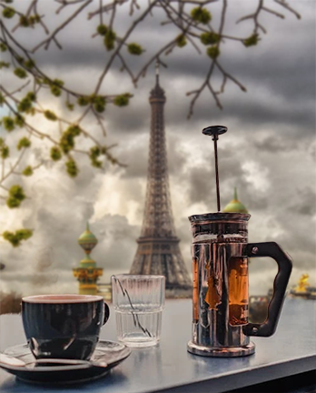 Eiffel-Tower-View-with-French-Press A French press coffee maker and cup set against a dramatic Paris backdrop with the Eiffel Tower, reflecting the rich history and international roots of the French press brewing method