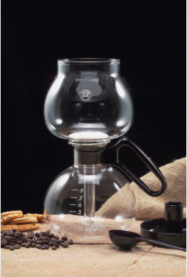 The Yama Siphon Vacuum Coffee Maker displayed on a burlap cloth with coffee beans and cookies, portraying a ready-to-brew setup that emphasizes simplicity and the hands-on approach of siphon brewing.