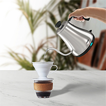 A stainless steel gooseneck kettle precisely pouring hot water into a pour over coffee dripper for even saturation and optimal flavor extraction.