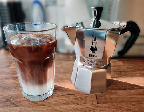 Moka-Pot-Iced-Latte-Recipe A Moka Pot next to a refreshing glass of iced latte, illustrating the simple pleasure of a homemade Moka Pot iced coffee, perfect for a warm day.